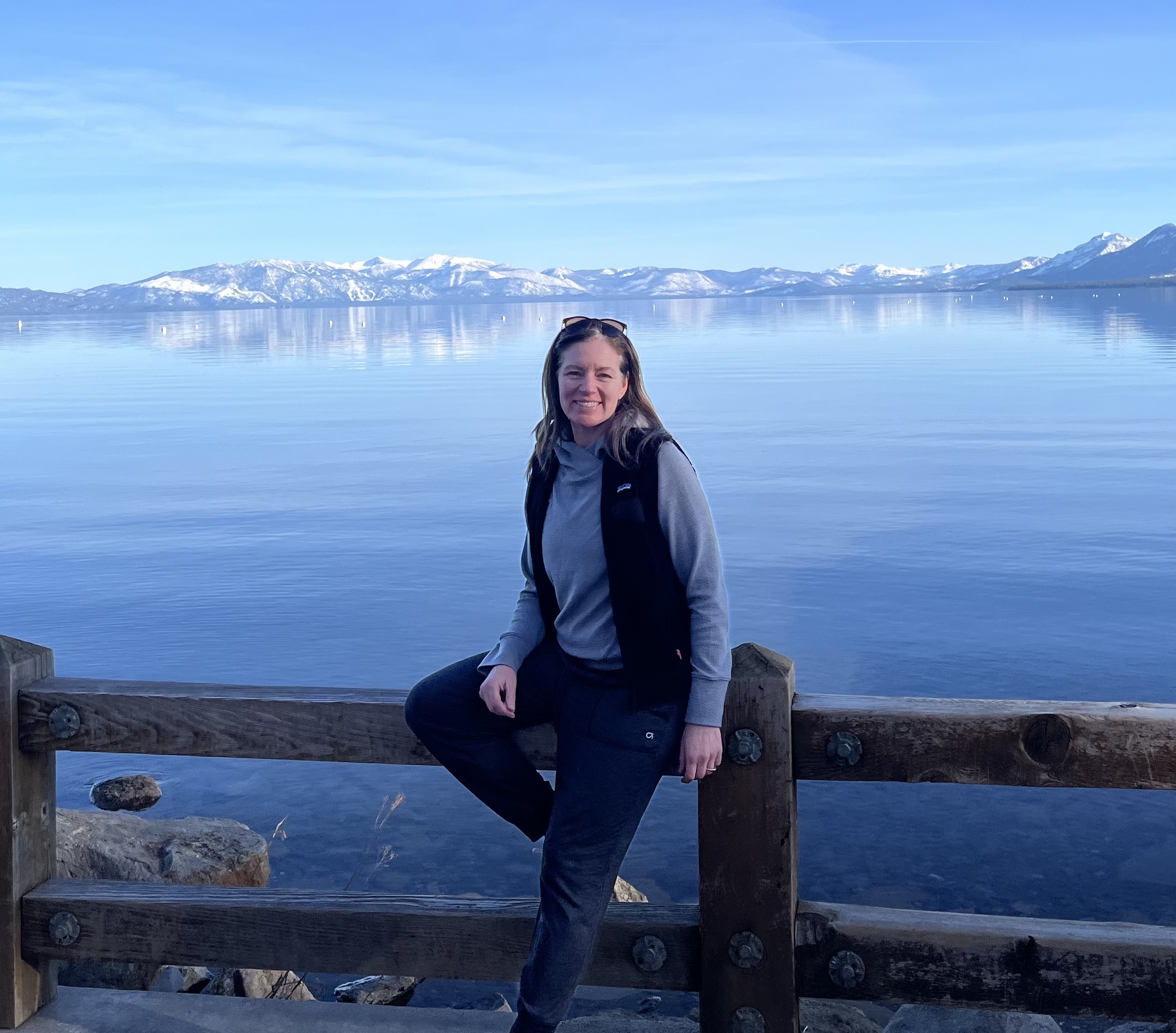 Dr. Mary Parman standing at Lake Tahoe with snow-capped mountains in the background